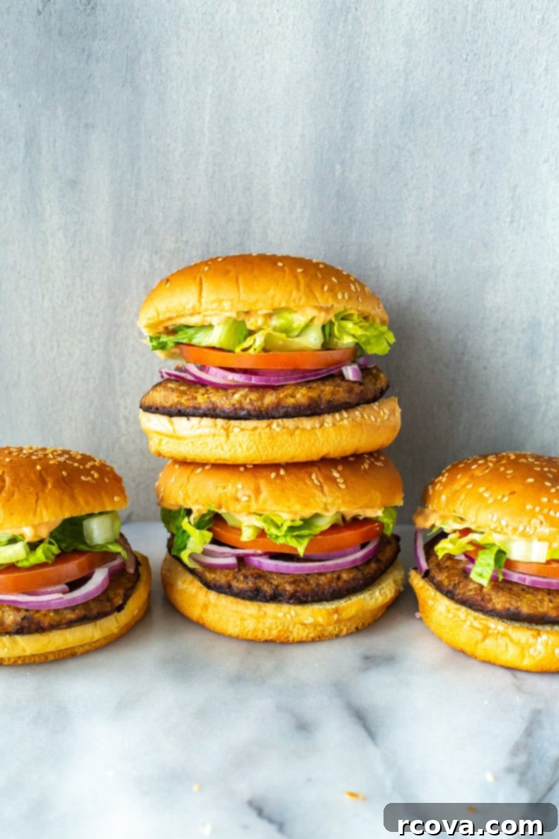 Succulent Turkey Burgers The Ultimate Recipe 9 A close-up of a stack of two juicy turkey burgers with melted cheese, fresh lettuce, tomatoes, and pickles on toasted buns.