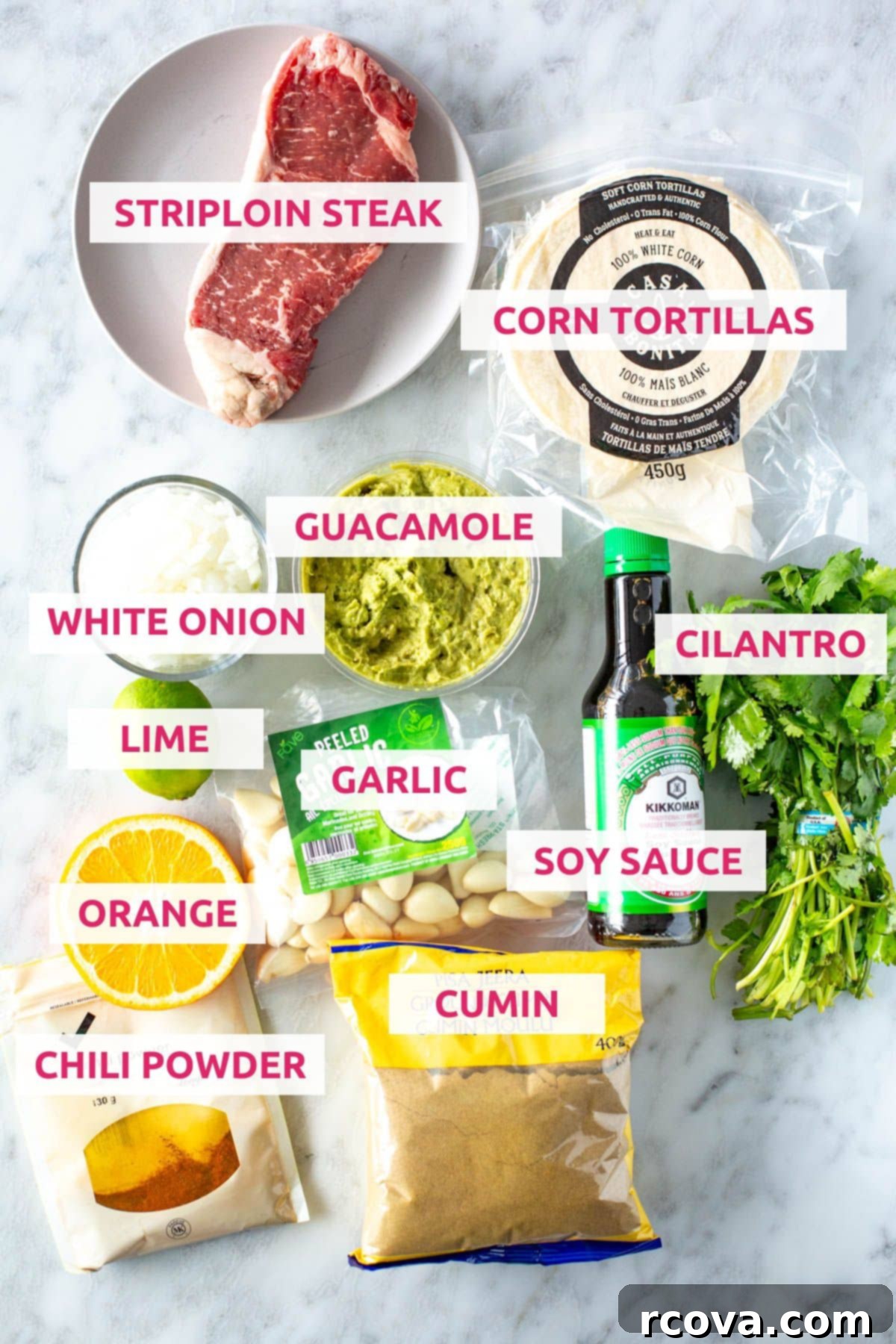 Sizzling Carne Asada Tacos 4 Ingredients for carne asada tacos: striploin steak, corn tortillas, white onion, guacamole, lime, garlic, soy sauce, cilantro, orange, chili powder and cumin, neatly arranged on a rustic wooden board.