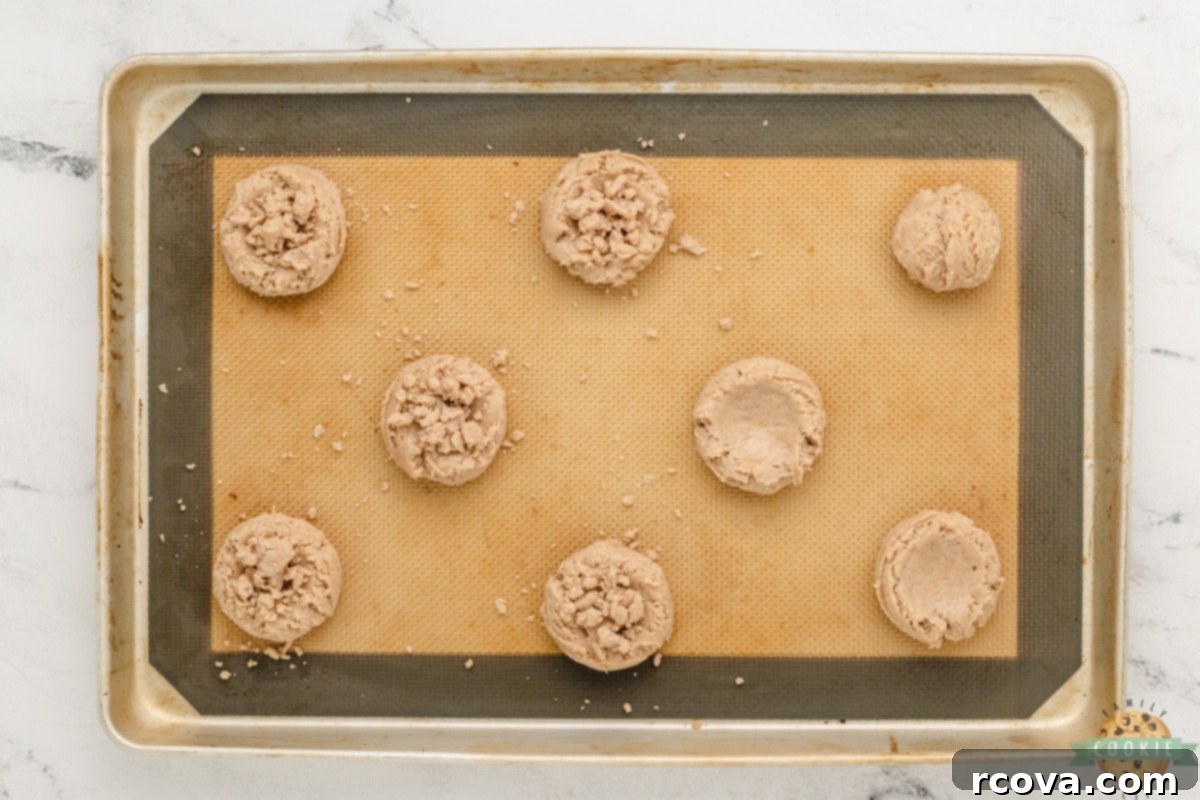Cinnamon Streusel Cookies 11 Cookie dough balls with indentations being topped with cinnamon streusel crumb before baking.
