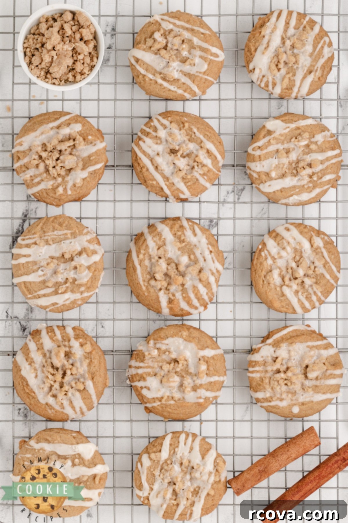 Cinnamon Streusel Cookies 17 Close-up of baked cinnamon cookies with crumb topping and vanilla glaze on a cooling rack.
