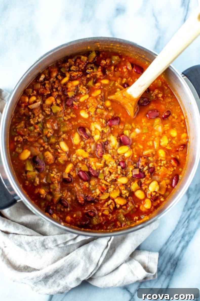 Unlock Wendy's Chili Secret 9 A top-down shot of a bowl of Wendy's Chili Copycat, with cheese and a spoon, against a rustic wooden background.