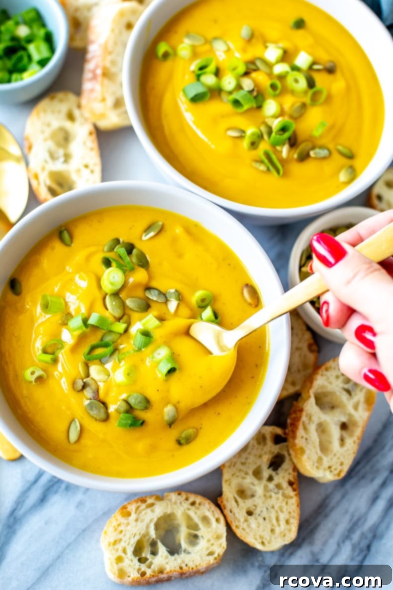 Simply Irresistible Kabocha Squash Soup 8 A beautifully composed flat lay of a bowl of Kabocha Squash Soup with a spoon, garnished with pumpkin seeds and fresh herbs, alongside bread.
