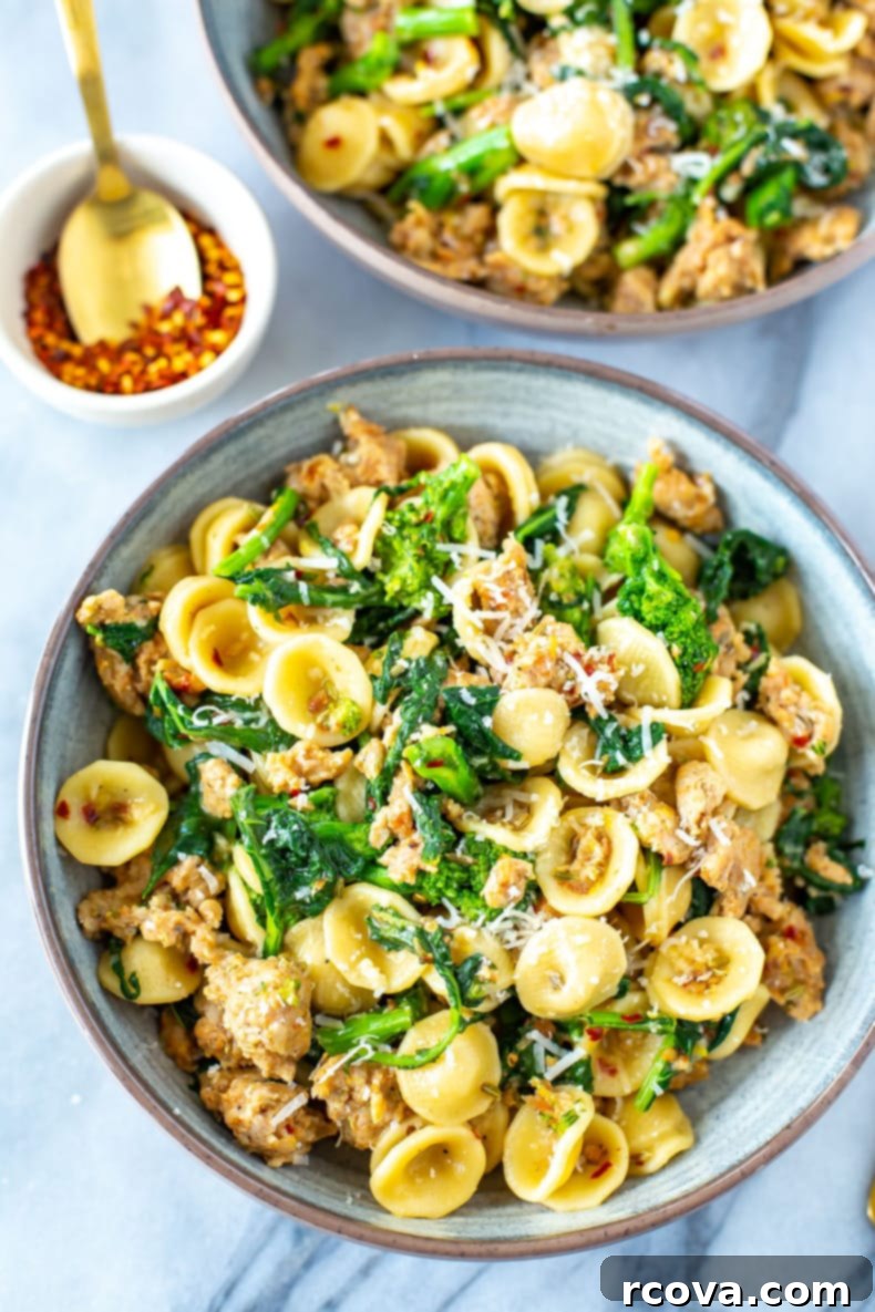 Rustic Orecchiette with Sausage and Broccoli Rabe 8 A beautifully plated close-up of Orecchiette with Sausage and Broccoli Rabe in a white bowl, ready to be served, garnished with fresh Parmesan cheese and chili flakes.