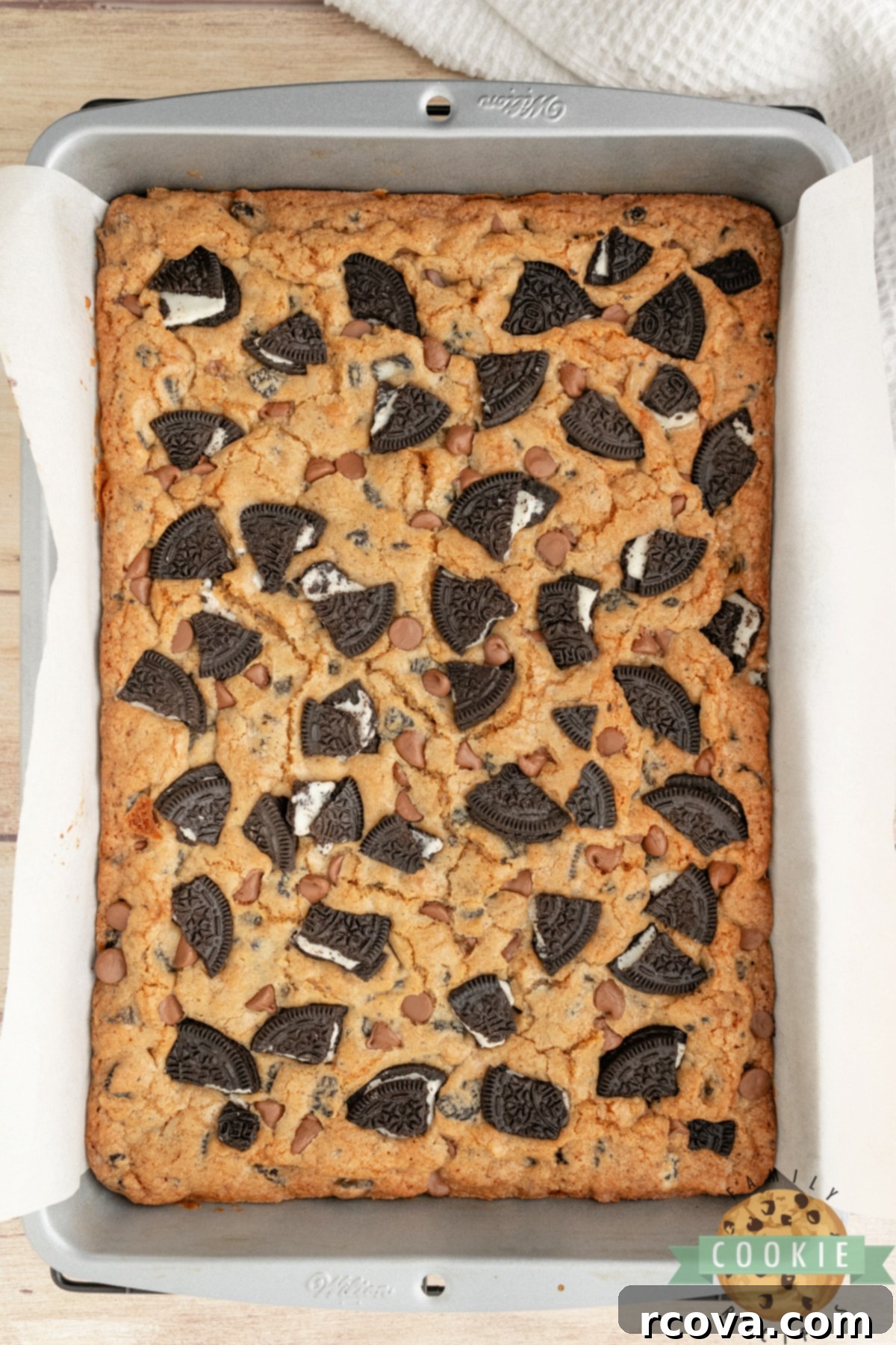 Ultimate Oreo Bars 6 Freshly baked Oreo Cookie Bars cooling in a parchment-lined baking pan, showcasing golden edges and a rich, dark center.