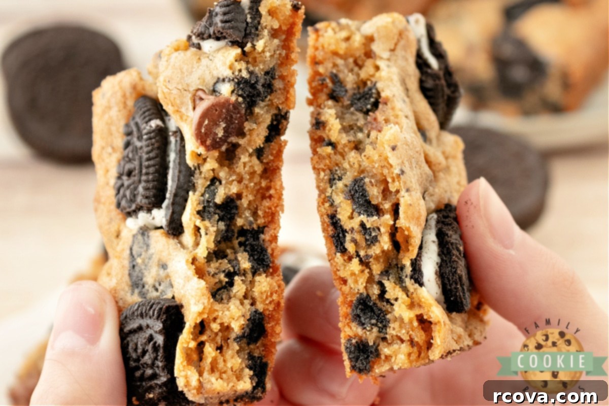 Ultimate Oreo Bars 8 A perfectly baked Oreo cookie bar broken in half, revealing its soft, chewy interior filled with crushed Oreos.