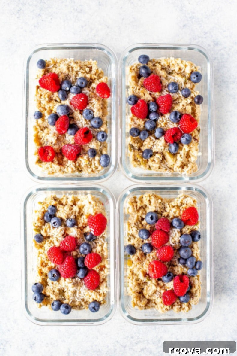 Power-Packed Protein Oats 2 Four glass meal prep containers, each with a serving of high protein oatmeal topped with fresh berries and seeds.