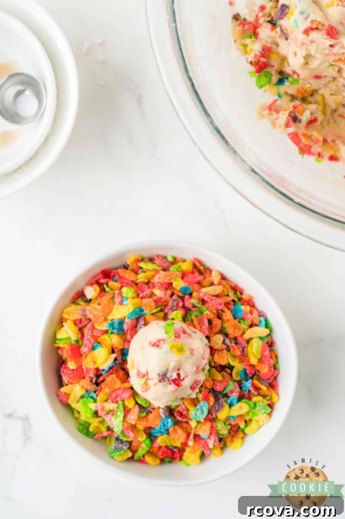 Vibrant Cereal Cookie Delights 10 Rolling a round ball of cookie dough in a bowl of Fruity Pebbles cereal.