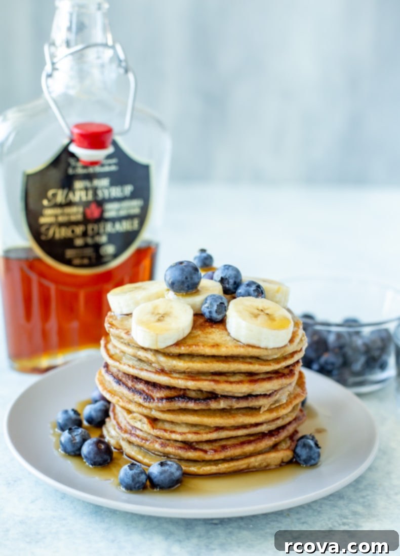 Wholesome 5-Ingredient Gluten-Free Banana Oat Pancakes 2 A stack of golden brown banana oat pancakes drizzled with maple syrup, garnished with fresh berries and sliced bananas, ready for a healthy and delicious breakfast.