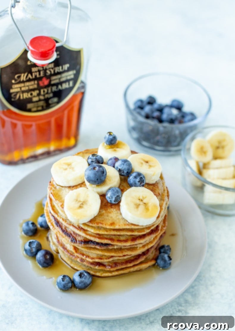 Wholesome 5-Ingredient Gluten-Free Banana Oat Pancakes 8 A towering stack of perfectly golden, fluffy banana oat pancakes on a pristine white plate, with a drizzle of syrup, ready to be enjoyed as a healthy and satisfying breakfast.