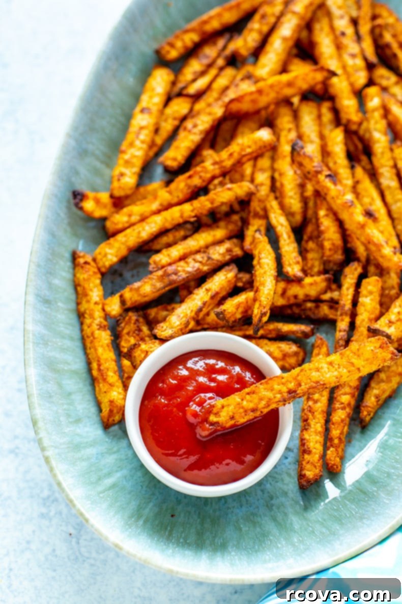 Healthy Crispy Air Fryer Jicama Fries 9 A generous serving of crispy jicama fries in an air fryer basket, perfectly golden brown and seasoned. They are arranged appealingly, emphasizing their crunchy texture and appetizing appeal as a low-carb alternative.