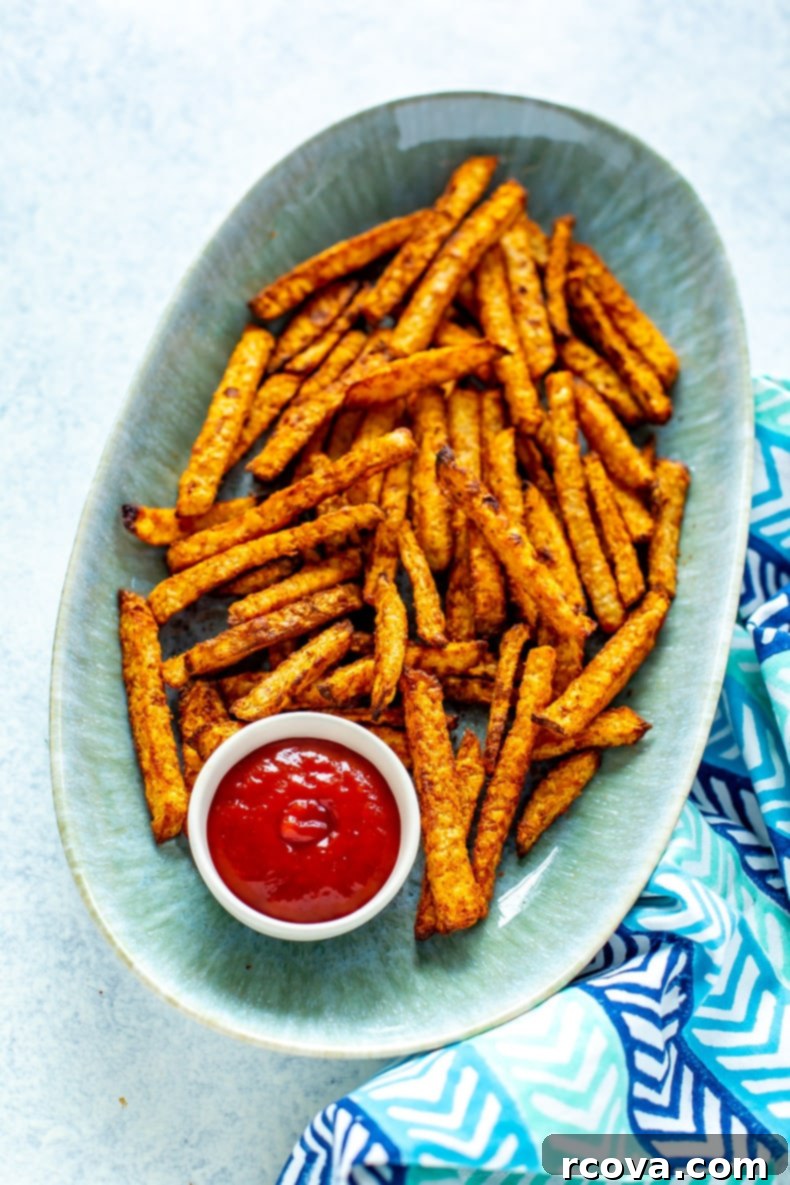 Healthy Crispy Air Fryer Jicama Fries 10 A vibrant, close-up image of a full bowl of golden, crispy low-carb jicama fries, garnished with fresh green herbs. The background is softly blurred, highlighting the inviting texture and deliciousness of the seasoned jicama fries.
