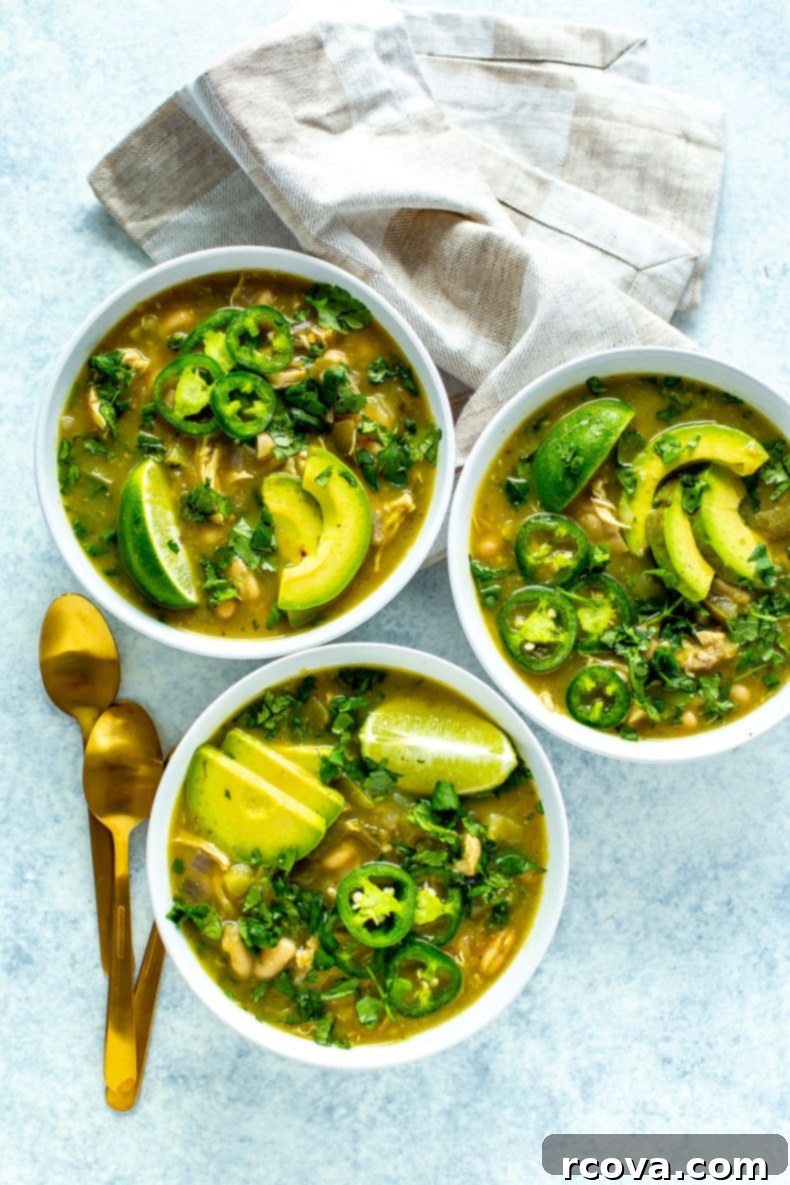 The Easiest Green Chili Ever 2 A large pot of the best green chili with tender pulled chicken, garnished with fresh cilantro and lime wedges.