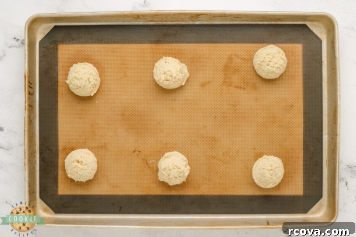 Decadent Orange Fudge Cookies 9 Uniformly scooped orange cookie dough balls arranged on a parchment-lined baking sheet.