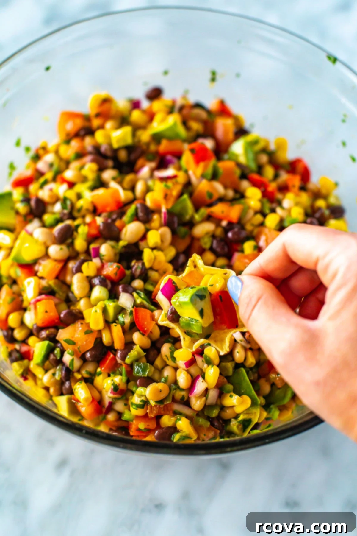 Over 25 Delicious No-Cook Recipes for Summer 11 A hand with a tortilla chip scooping up cowboy caviar from a bowl.