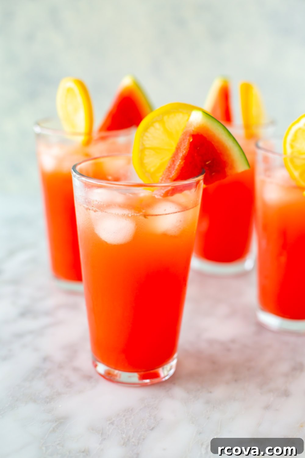 Summer's Coolest Sips 6 Several tall glasses brimming with bright pink watermelon lemonade, garnished with fresh mint and lemon slices.