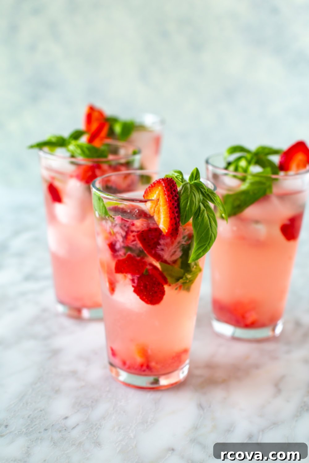 Summer's Coolest Sips 9 Glasses filled with effervescent strawberry basil fizz, garnished with strawberry slices and fresh basil leaves.