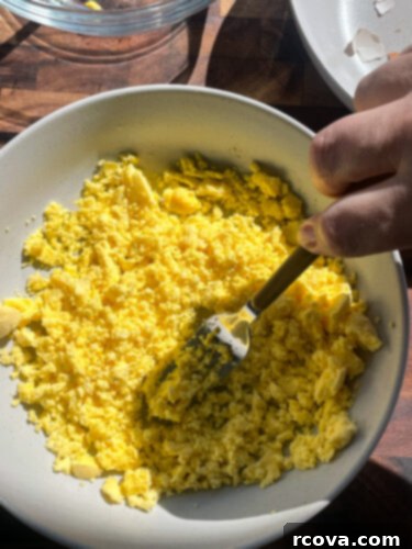 Fiery Sriracha Bacon Deviled Eggs 5 bowl of egg yolks, mashed with a fork to prepare deviled egg filling