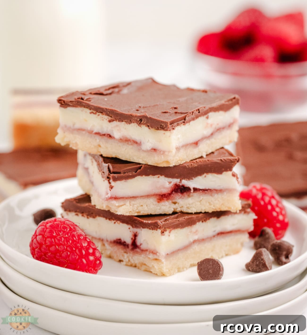 Gourmet Raspberry Chocolate Bars 2 A stack of delicious raspberry chocolate bars with a crumbly base and smooth chocolate topping, garnished with fresh raspberries.