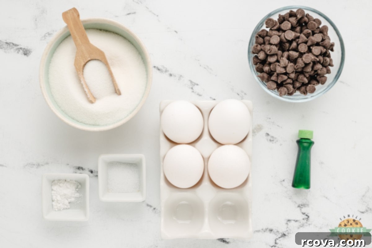 Cool Mint Chocolate Chip Meringue Clouds 3 Selection of fresh ingredients for Mint Chocolate Chip Meringue Cookies, including egg whites, mint extract, green food coloring, cream of tartar, salt, sugar, and mini chocolate chips.