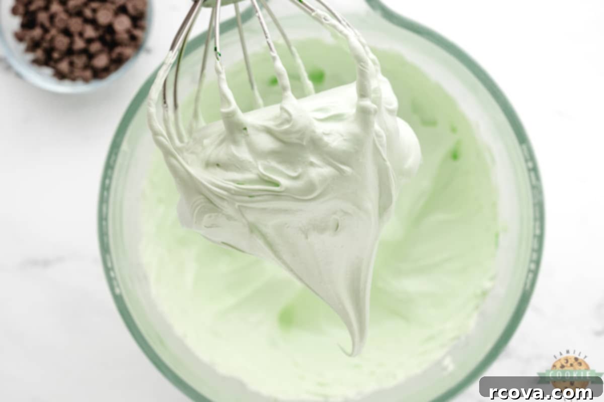 Cool Mint Chocolate Chip Meringue Clouds 6 Soft peaks forming in a green meringue mixture in a bowl, showing the initial stage of whipping.