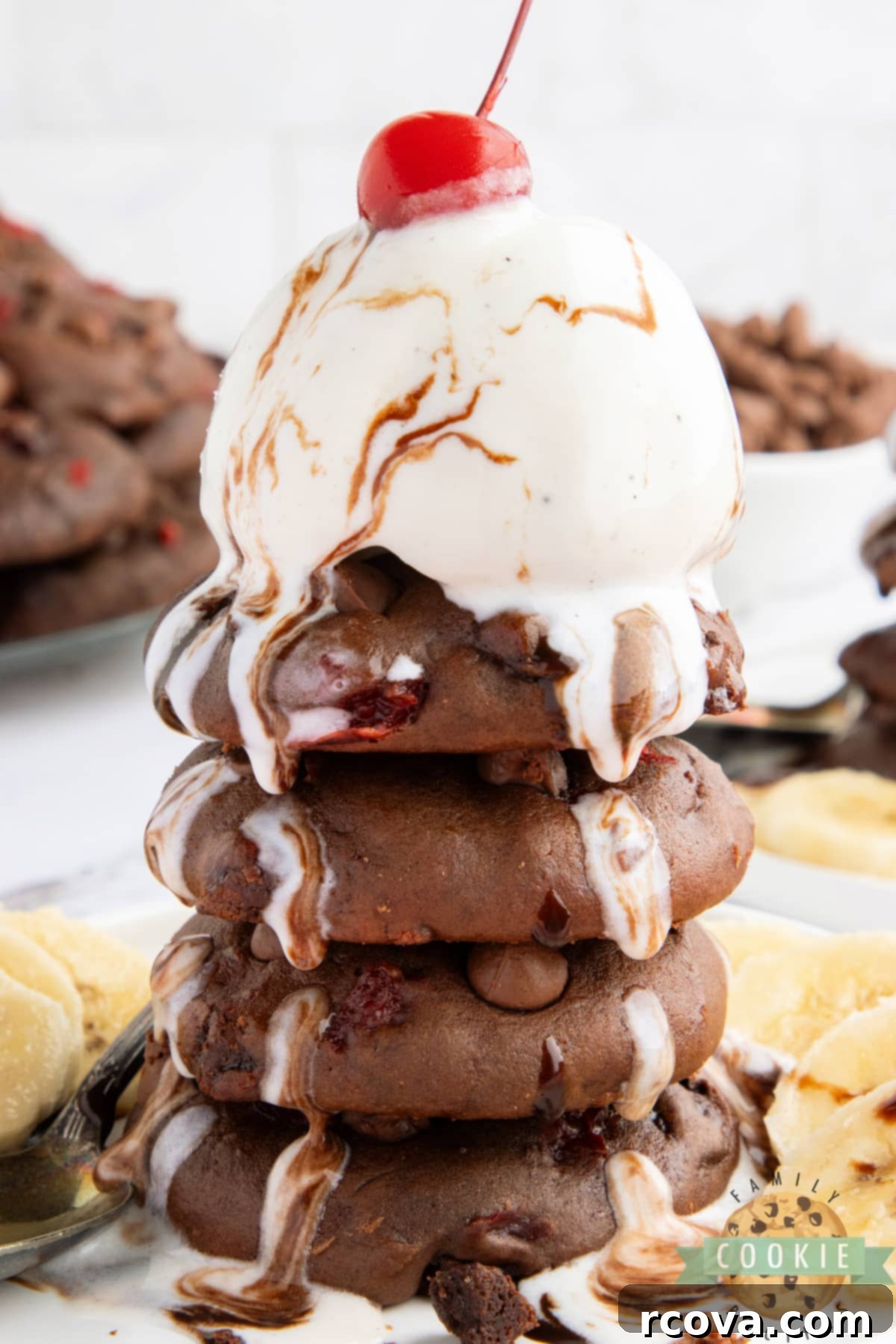 Double Chocolate Banana Split Dream Cookies 3 Close-up of baked chocolate cookies, revealing chunks of banana and bright red cherries embedded in the rich chocolate dough.