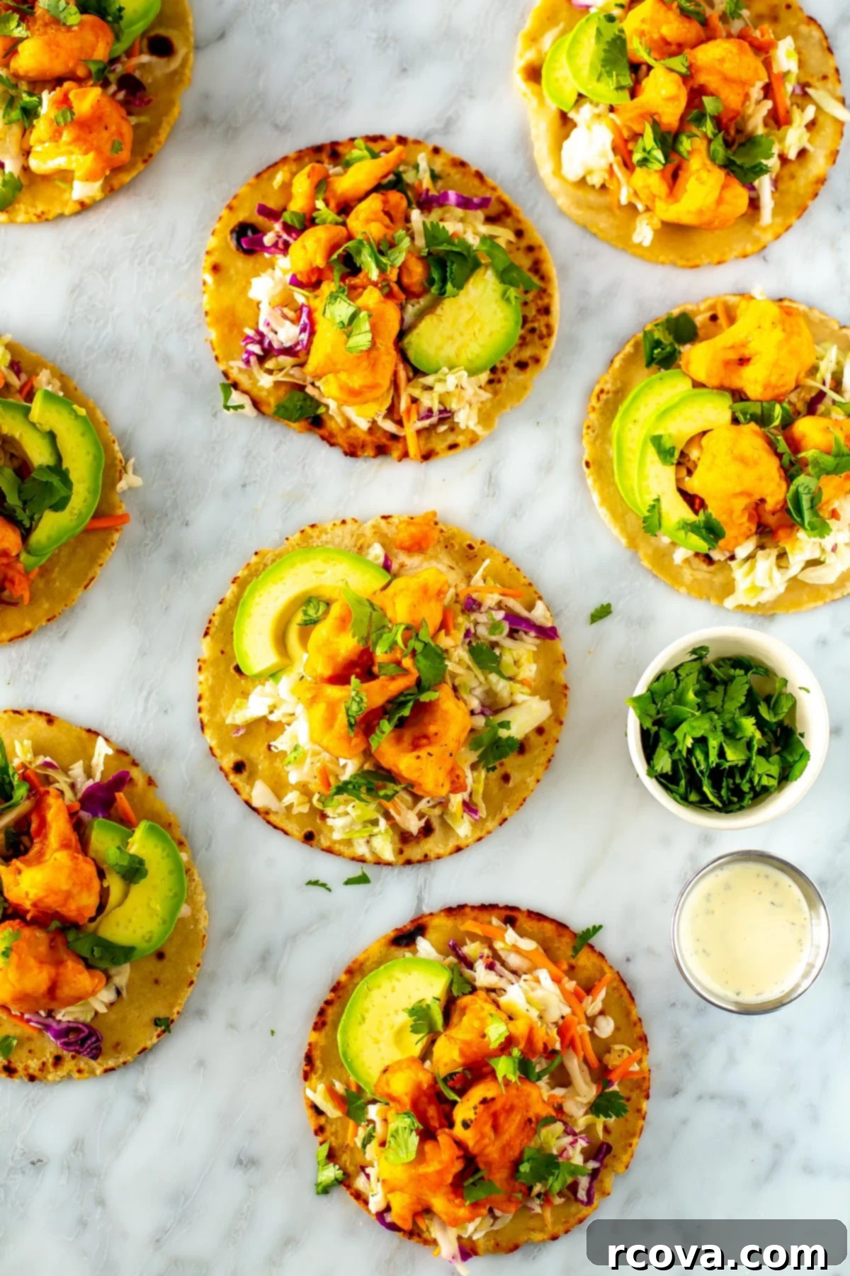 Zesty Buffalo Cauliflower Tacos 8 An overhead shot of several buffalo cauliflower tacos with little bowls of cilantro and ranch dressing on the side.