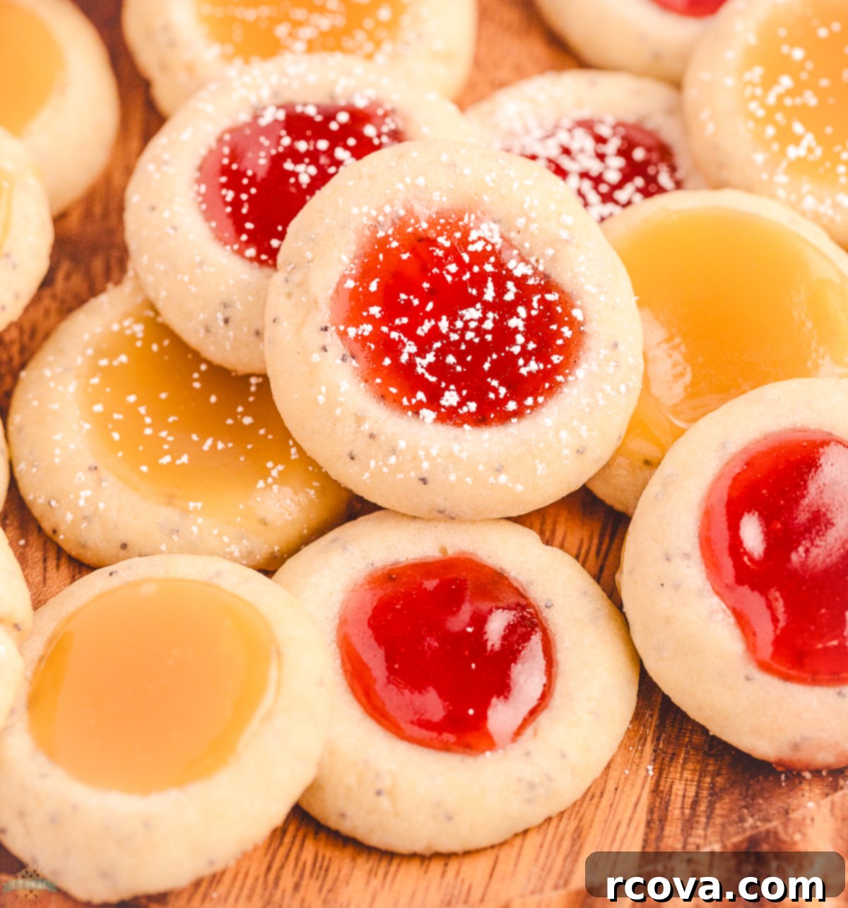 THUMBPRINT COOKIES WITH POPPY SEED 2 Vibrant Poppy Seed Thumbprint Cookies with glistening strawberry jam and bright lemon curd fillings on a white plate