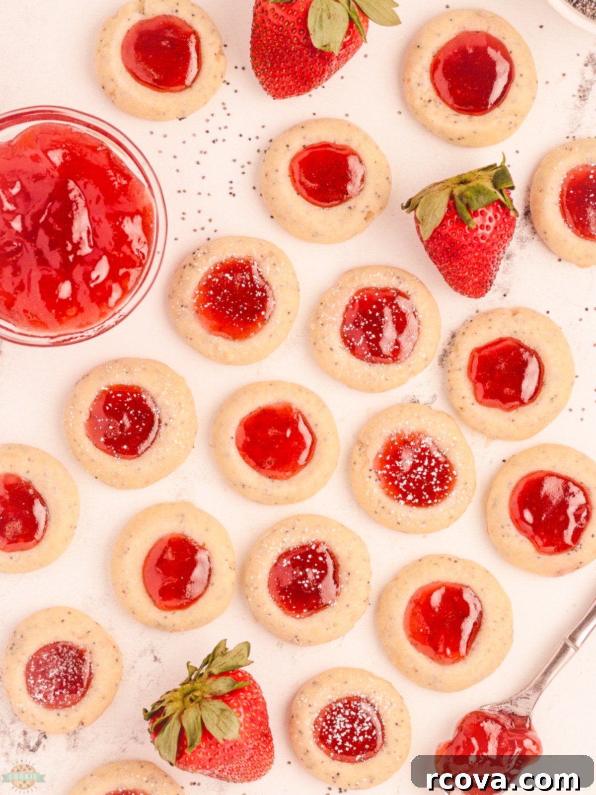 THUMBPRINT COOKIES WITH POPPY SEED 4 Freshly baked Poppy Seed Thumbprint Cookies, some filled with strawberry jam and others with lemon curd, cooling on a rack.