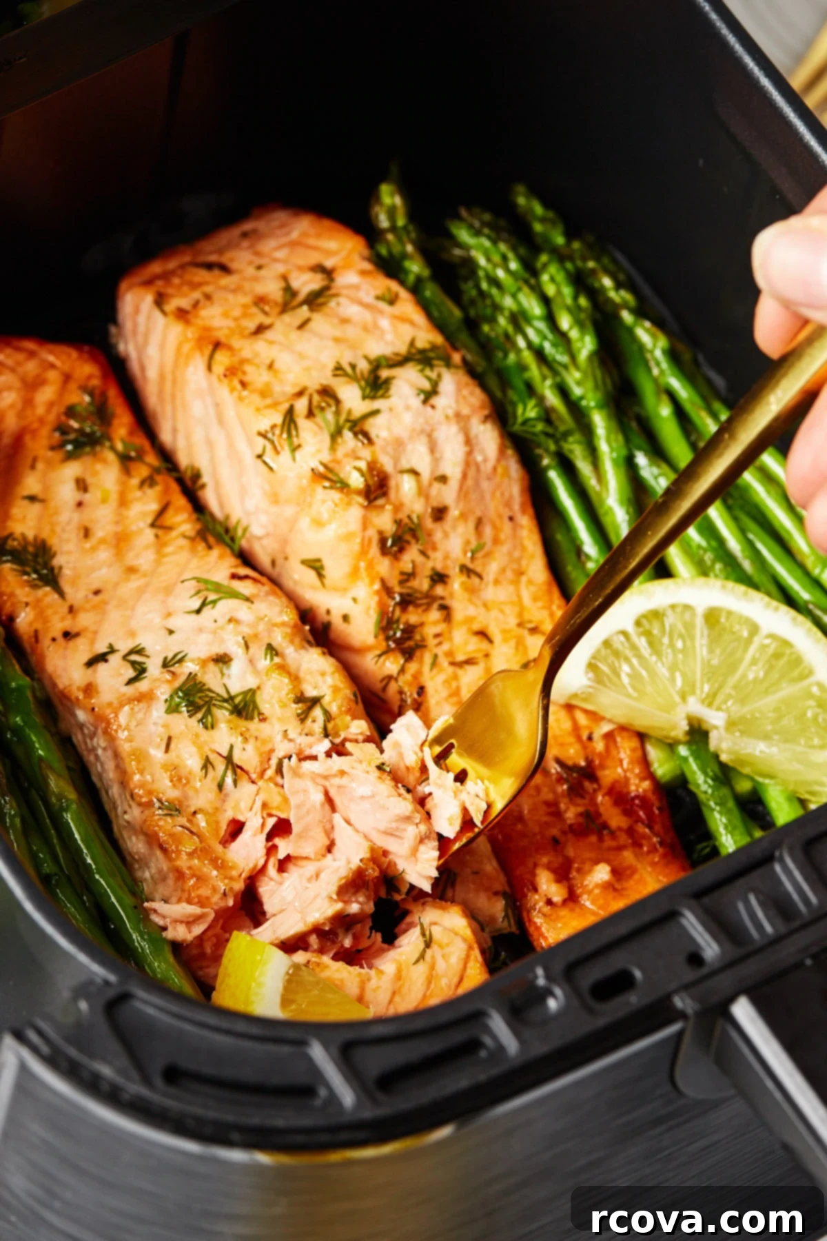 30-Minute Air Fryer Salmon 7 A close-up shot of a fork gently flaking perfectly cooked salmon inside an air fryer basket, highlighting its moist and tender texture.