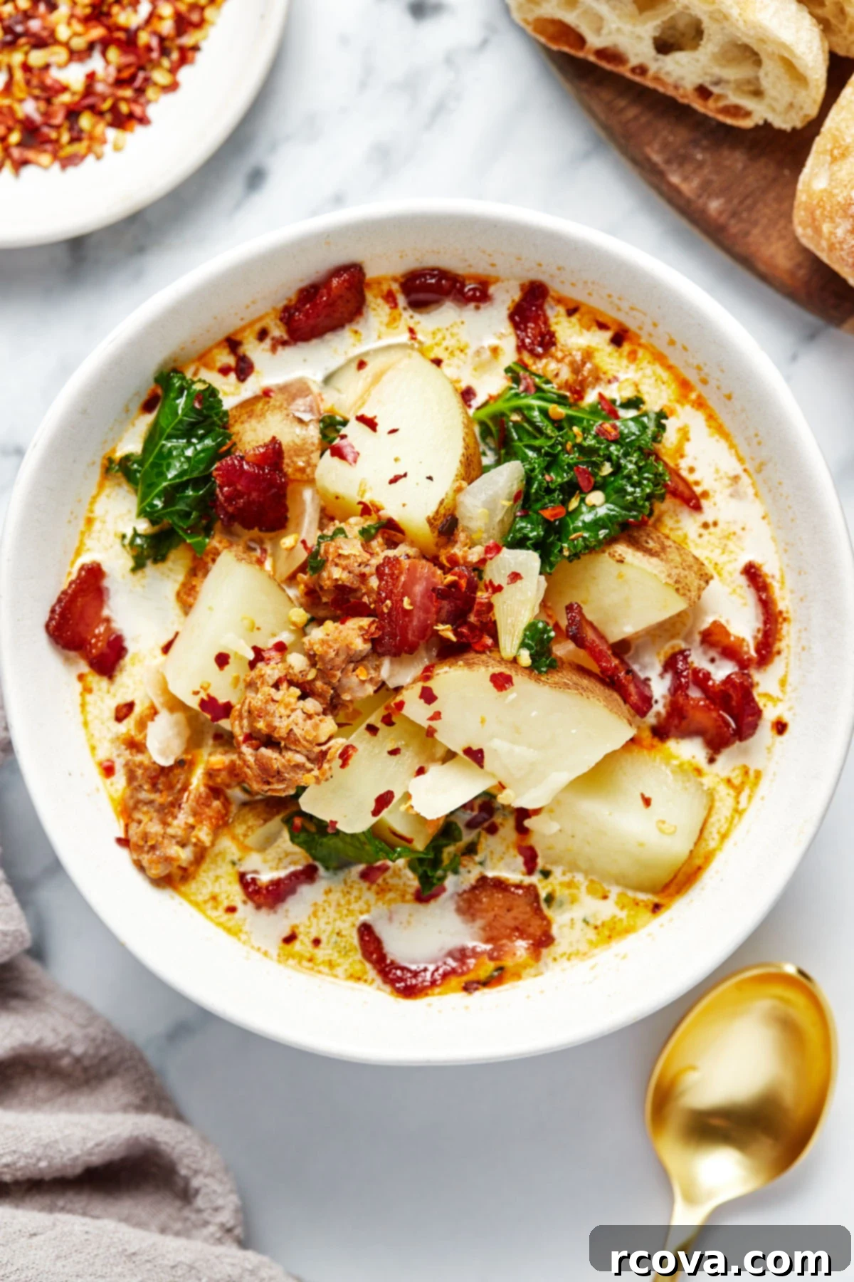 One Pot Restaurant-Style Zuppa Toscana 2 A beautiful bowl of Zuppa Toscana, garnished with red chili flakes and a slice of crusty bread on the side, ready to be enjoyed.