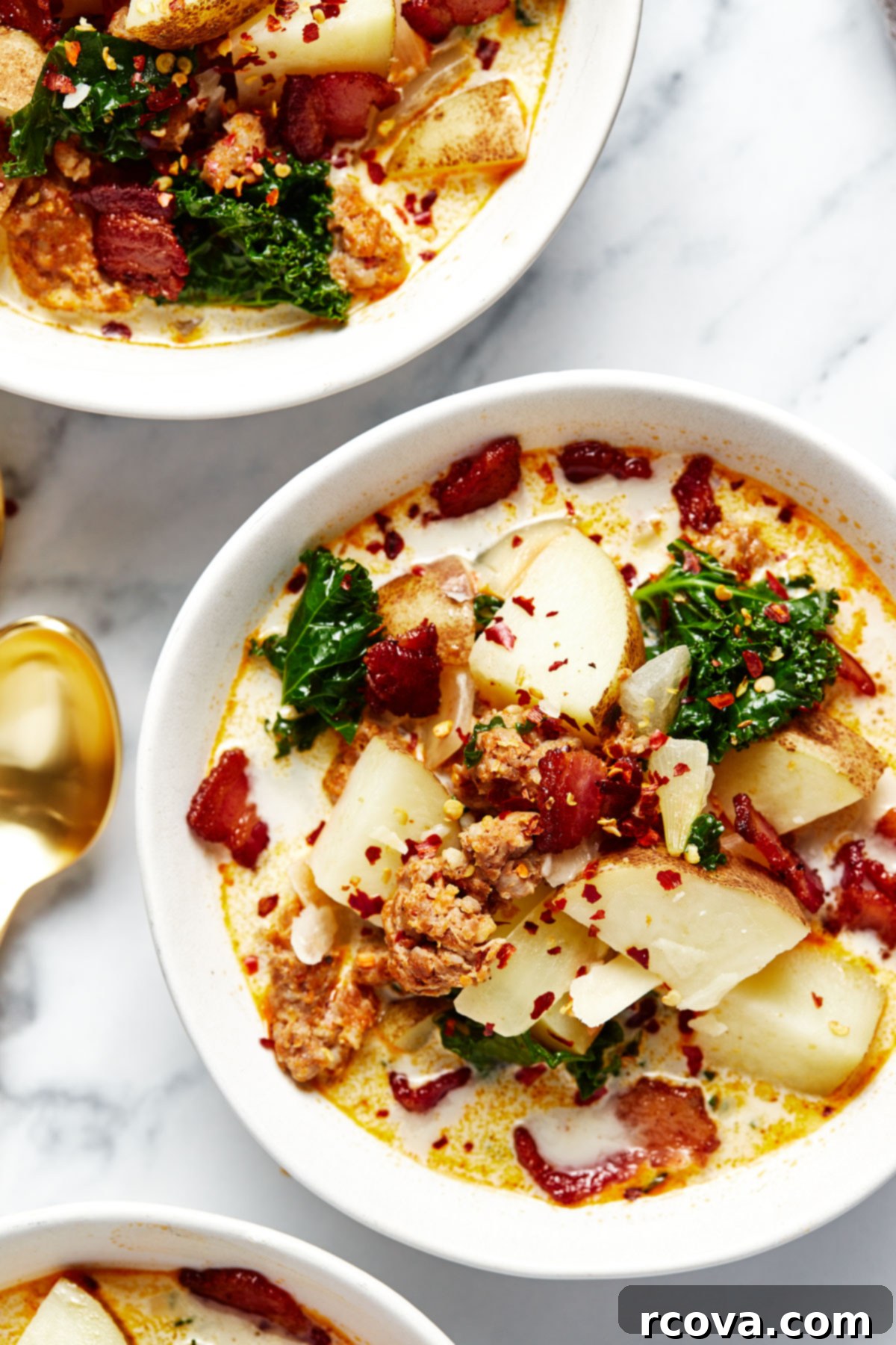 One Pot Restaurant-Style Zuppa Toscana 7 A visually appealing close-up of three bowls filled with freshly made Zuppa Toscana, showcasing the creamy broth, pieces of sausage, potatoes, and vibrant green kale.