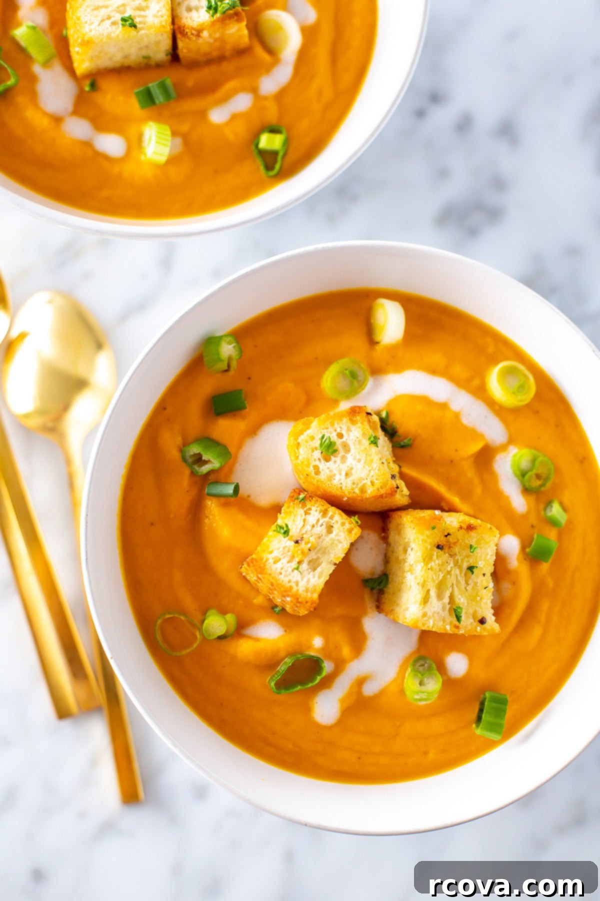 Velvety Vegan Coconut Carrot Ginger Soup 7 A close up of a bowl of creamy coconut carrot ginger soup topped with croutons.