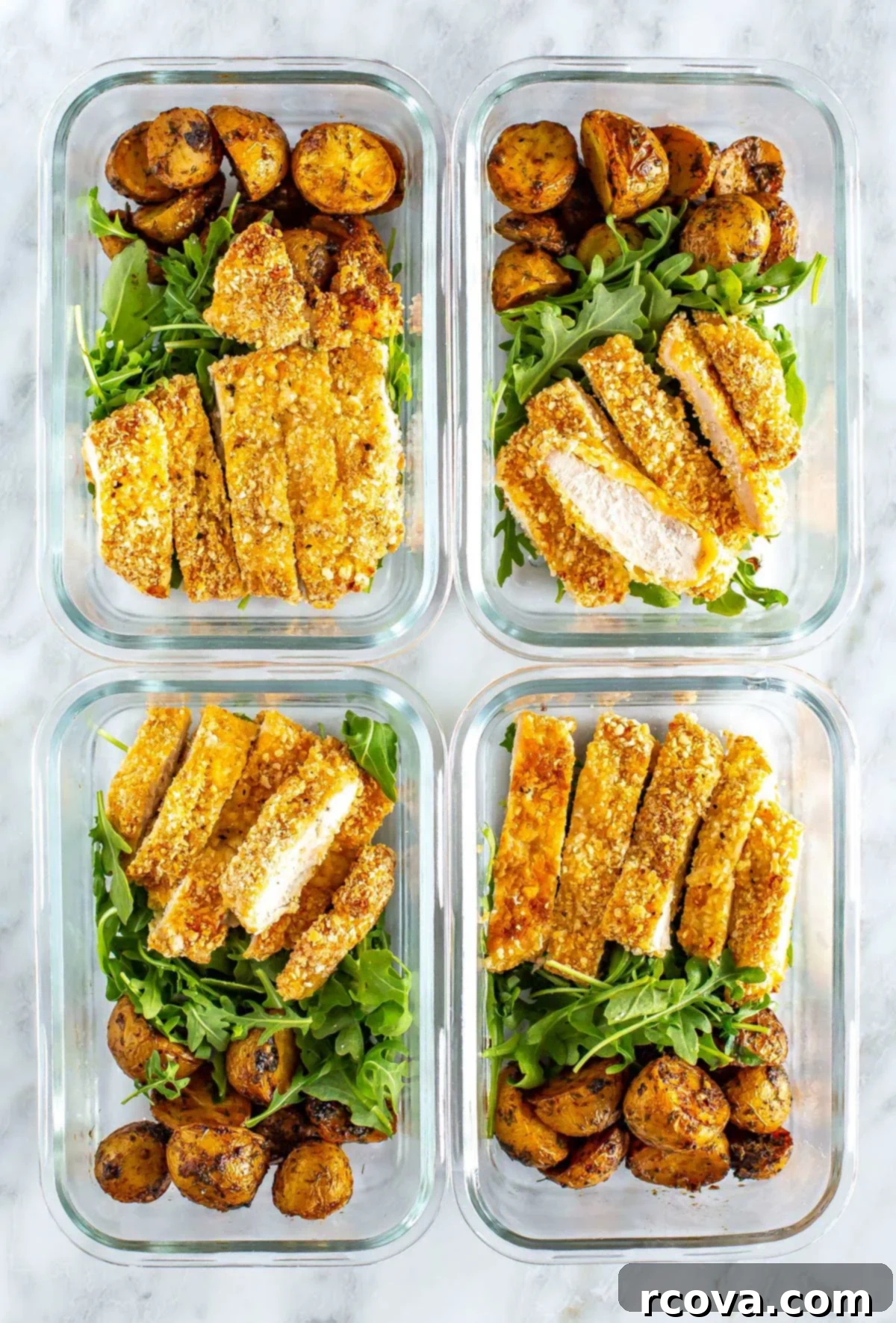 Crispy and Juicy Oven Baked Chicken Cutlets 8 Four perfectly portioned meal prep containers, each featuring a vibrant bed of fresh arugula, a serving of lemon dill potatoes, and a neatly sliced crispy chicken cutlet, showcasing a healthy and convenient meal solution.