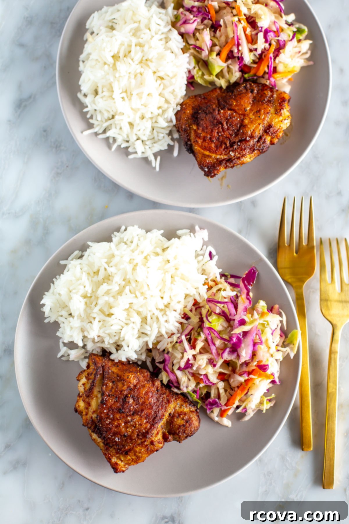 Versatile Air Fryer Chicken Thighs Bone In Or Boneless 2 Deliciously crispy and juicy air fryer chicken thighs served on a white plate with a side of fluffy white rice and creamy coleslaw for a complete meal.