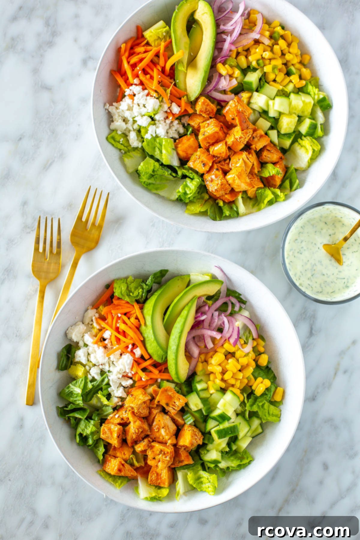 Lightened Up Buffalo Chicken Salad 2 Two bowls of buffalo chicken salad next to each other with ranch dressing on the side, showcasing the vibrant colors and fresh ingredients.