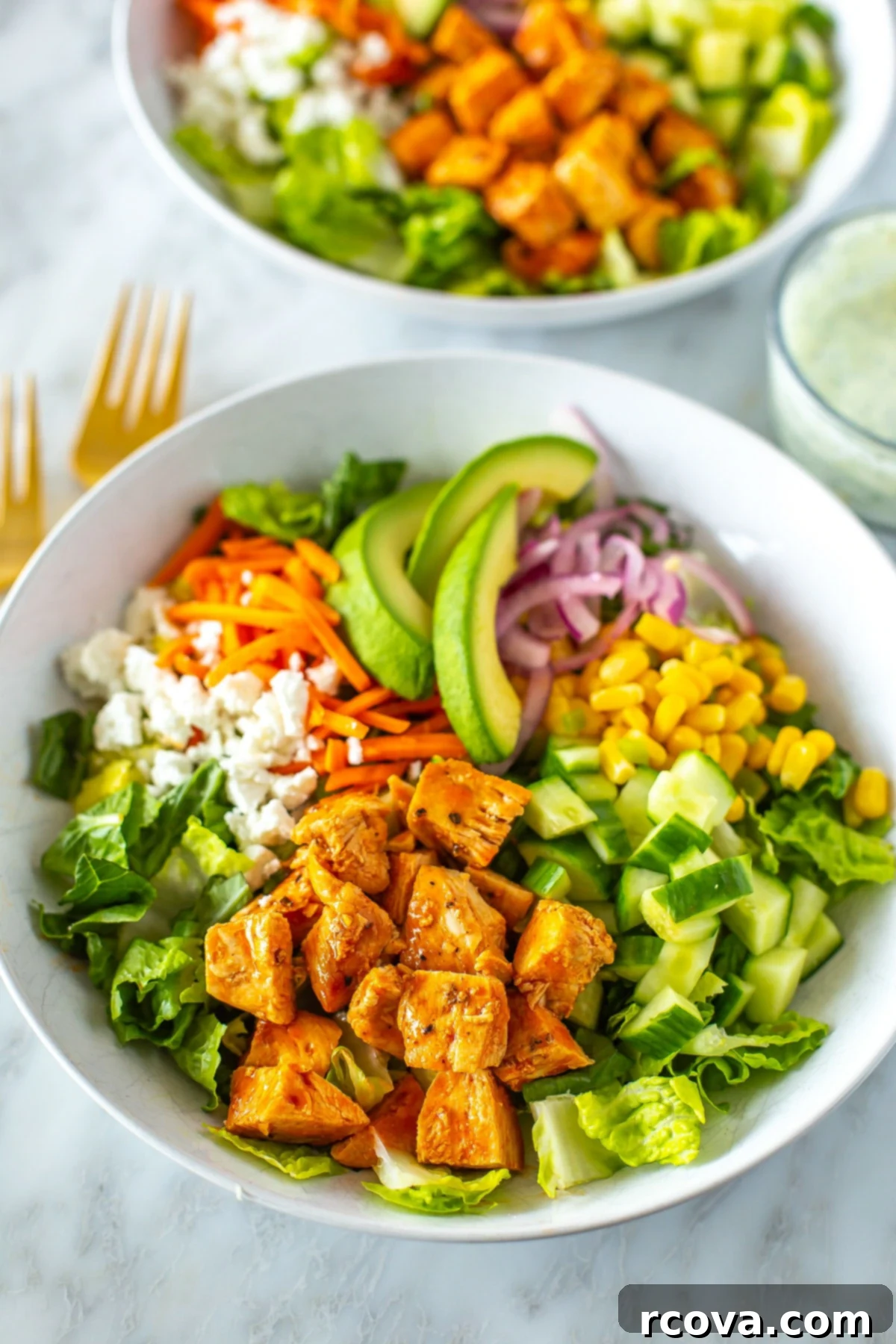 Lightened Up Buffalo Chicken Salad 8 A close-up of a bowl of buffalo chicken salad with a bowl of ranch dressing on the side, highlighting the freshness.