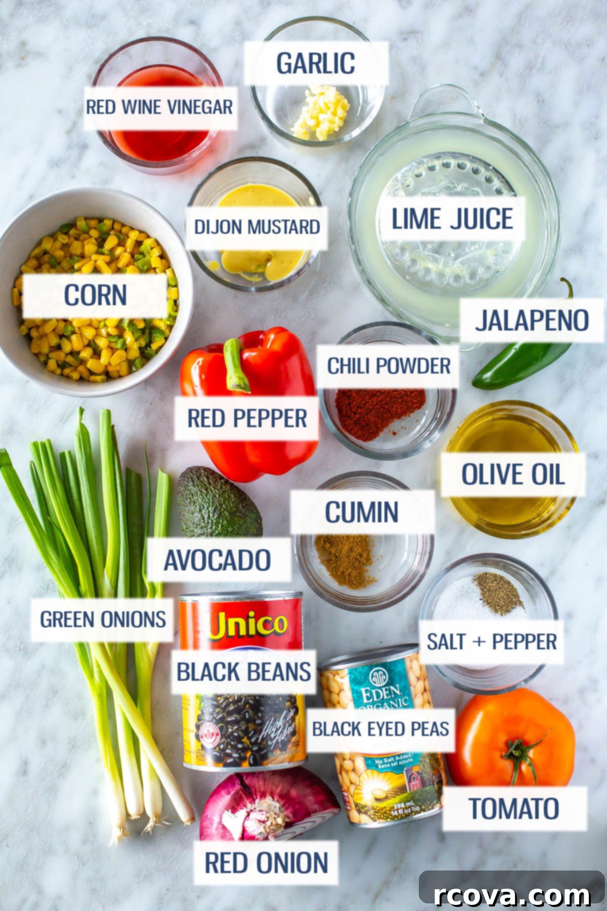 The Only Cowboy Caviar Recipe You'll Ever Need 4 Ingredients for cowboy caviar laid out: red wine vinegar, garlic, corn, dijon mustard, lime juice, green onions, red bell pepper, chili powder, jalapeno, avocado, cumin, olive oil, black beans, black eyed peas, red onion, tomato, salt and pepper.