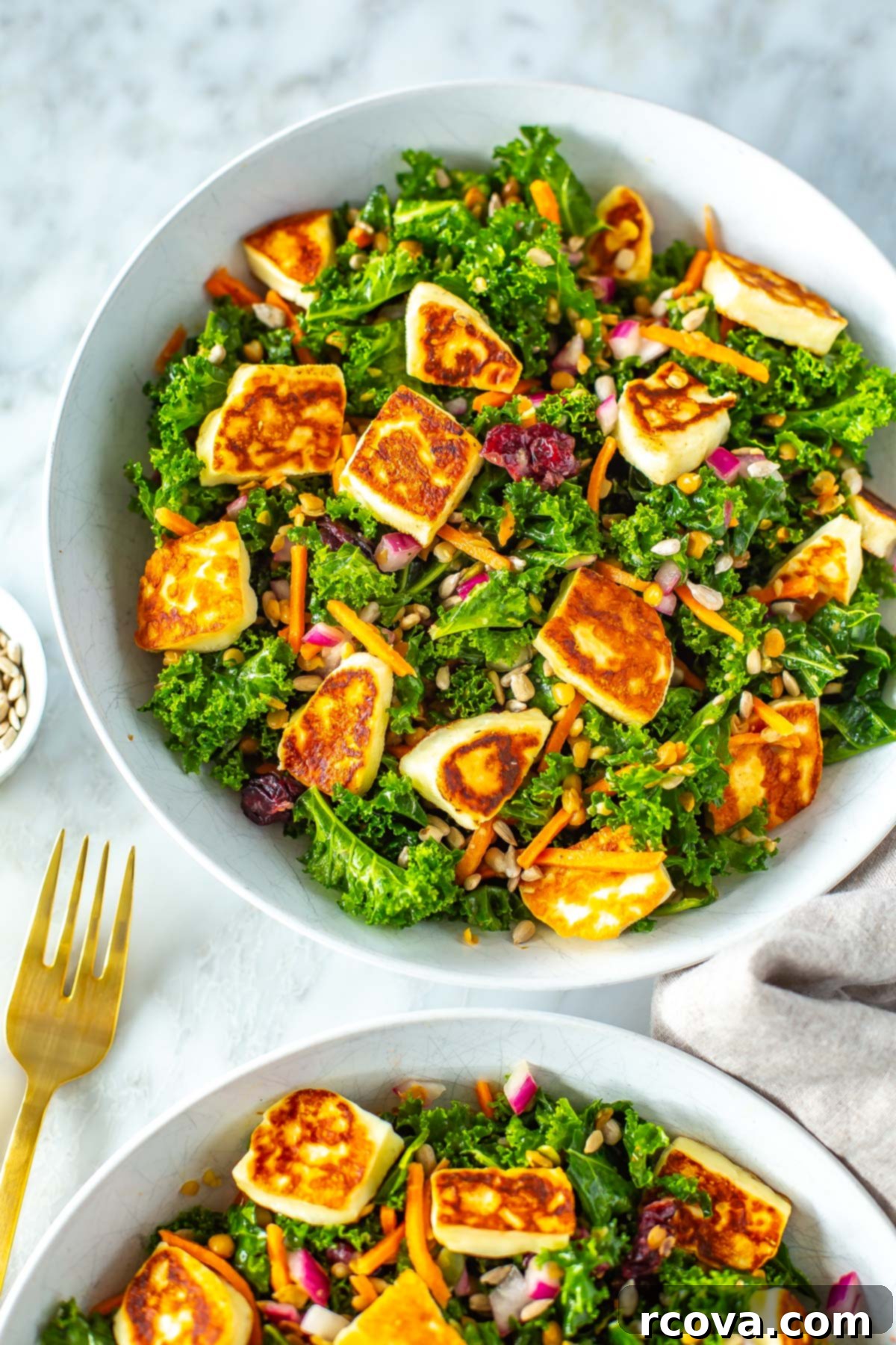 Viral Kale Salad Sensation 6 A close-up of a vibrant bowl of kale salad, generously topped with golden-brown halloumi cheese, showcasing a healthy and appetizing meal.