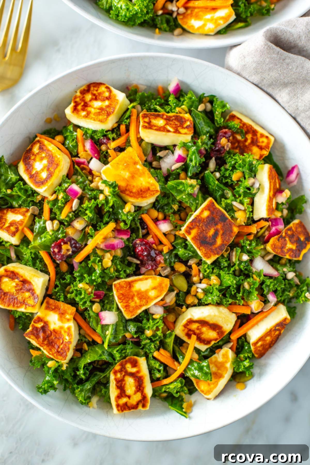 Viral Kale Salad Sensation 7 A close-up shot of a bowl of fresh kale salad, featuring tender greens, colorful toppings, and savory halloumi cheese.