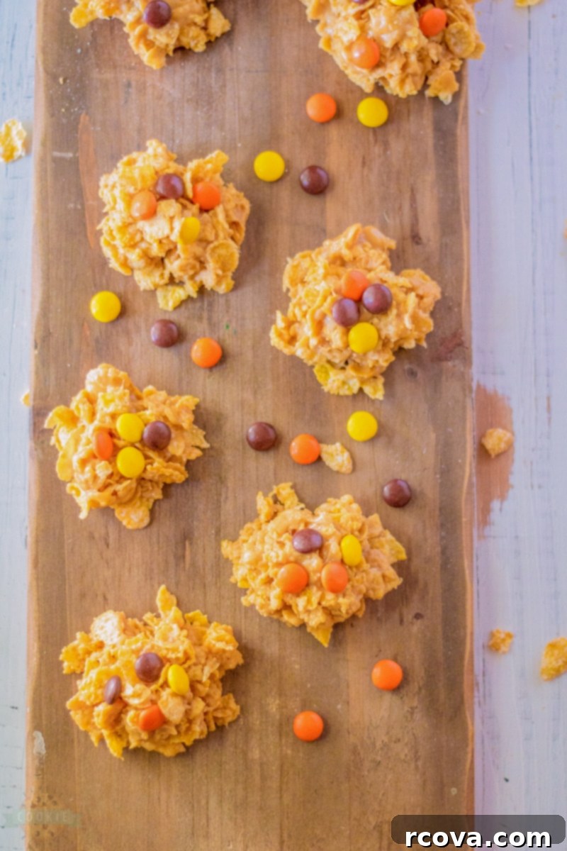 Reeses Cornflake Peanut Butter Crunch Cookies 7 Close-up of a stack of no-bake peanut butter cornflake cookies with Reese's Pieces candy on top, on a dark wooden surface