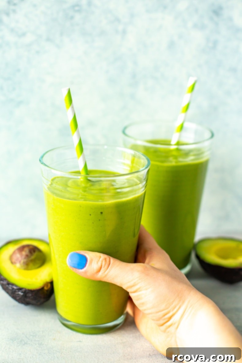 15 Power-Packed Protein Snacks 8 Vibrant green creamy avocado smoothie in a glass with a straw, garnished with mint.