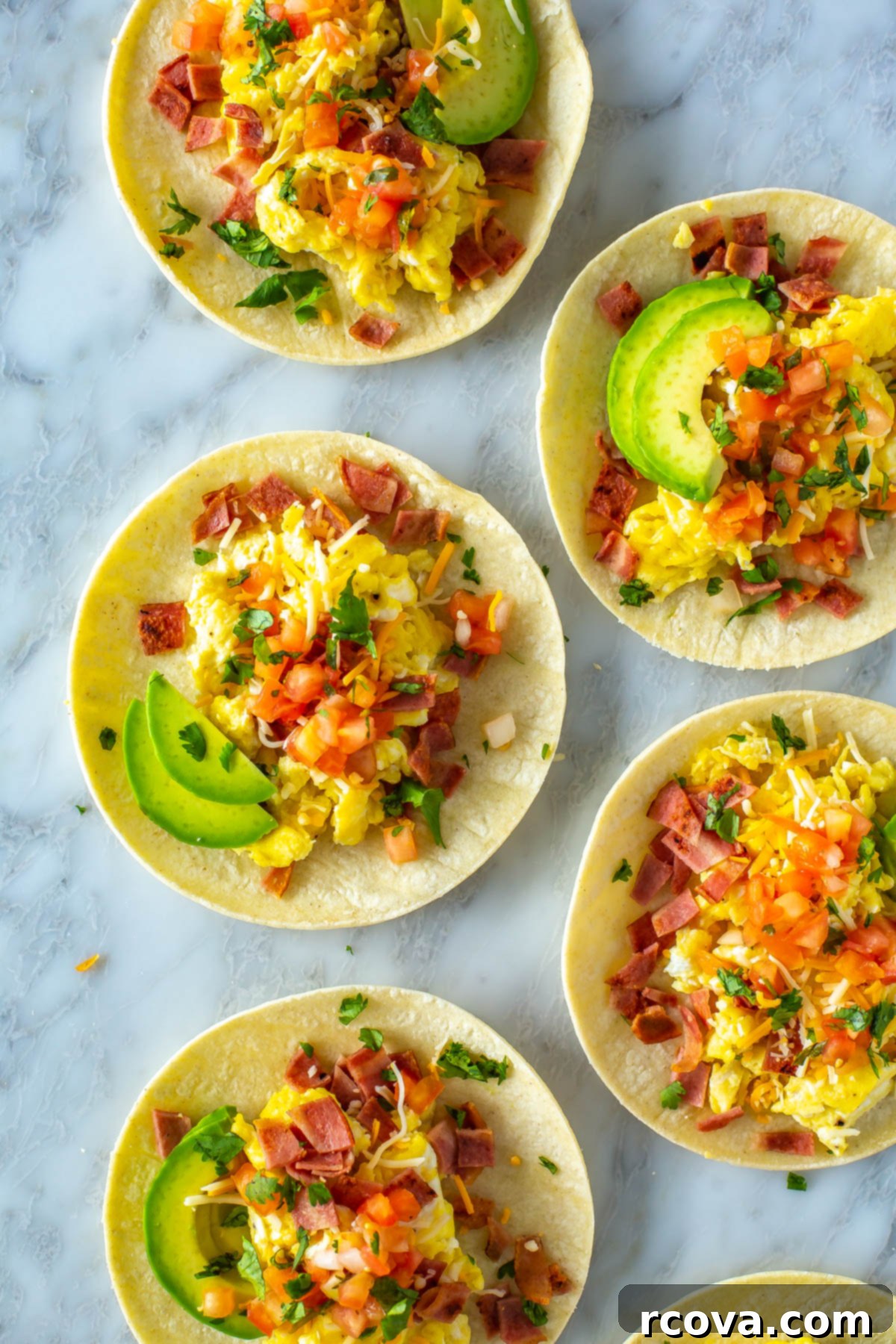 The Ultimate 30-Minute Breakfast Tacos 6 An inviting overhead shot of multiple breakfast tacos, generously loaded with scrambled eggs, crispy bacon, vibrant pico de gallo, creamy avocado, and melted cheese, artistically arranged on a serving board.