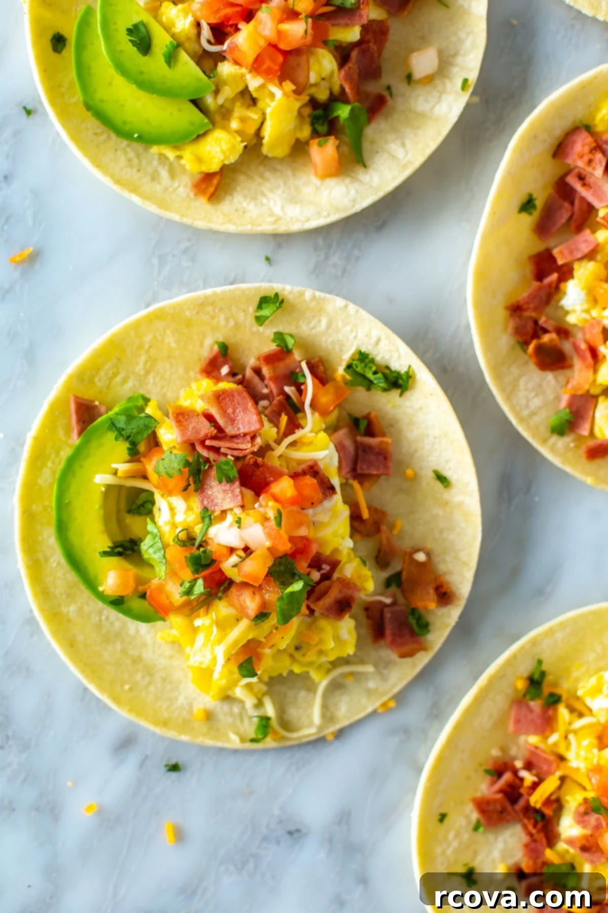 The Ultimate 30-Minute Breakfast Tacos 7 A vibrant close-up overhead shot of multiple breakfast tacos, showcasing perfectly cooked scrambled eggs, crispy bacon, fresh pico de gallo, creamy avocado slices, and melted cheese, highlighting their appetizing textures and colors.