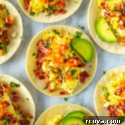 The Ultimate 30-Minute Breakfast Tacos 9 An overhead shot of breakfast tacos topped with eggs, bacon, pice de gallo, avocado and cheese.