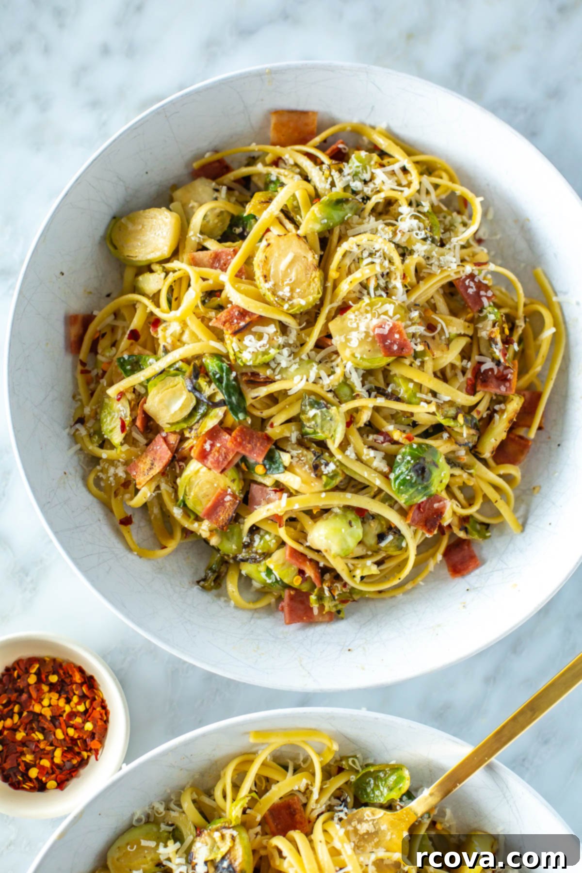 Bacon Brussels Sprouts Creamy Pasta 6 A close-up shot of a single bowl of creamy brussels sprouts pasta, generously topped with crispy bacon bits, fresh Parmesan, and a sprinkle of red chili flakes, highlighting the rich texture of the sauce and the vibrant green of the sprouts.