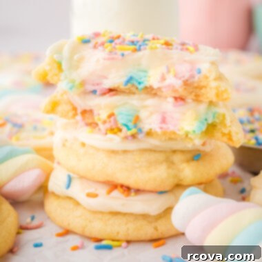 Gooey Marshmallow-Stuffed Cookies 5 Rainbow Marshmallow Surprise Cookies topped with creamy vanilla frosting and colorful sprinkles, showcasing the gooey marshmallow center.