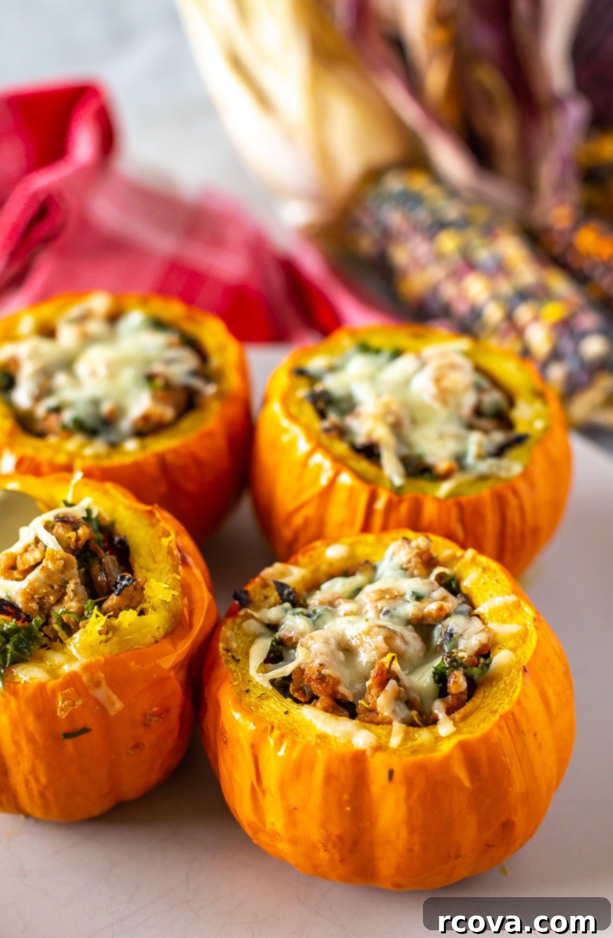 Unutulmaz Balkabağı Dolması Tarifi 2 Four beautifully cooked stuffed mini pumpkins, garnished with fresh herbs, resting on a rustic platter amidst autumnal decor like fall leaves and small gourds, ready to be served as a delightful fall meal.