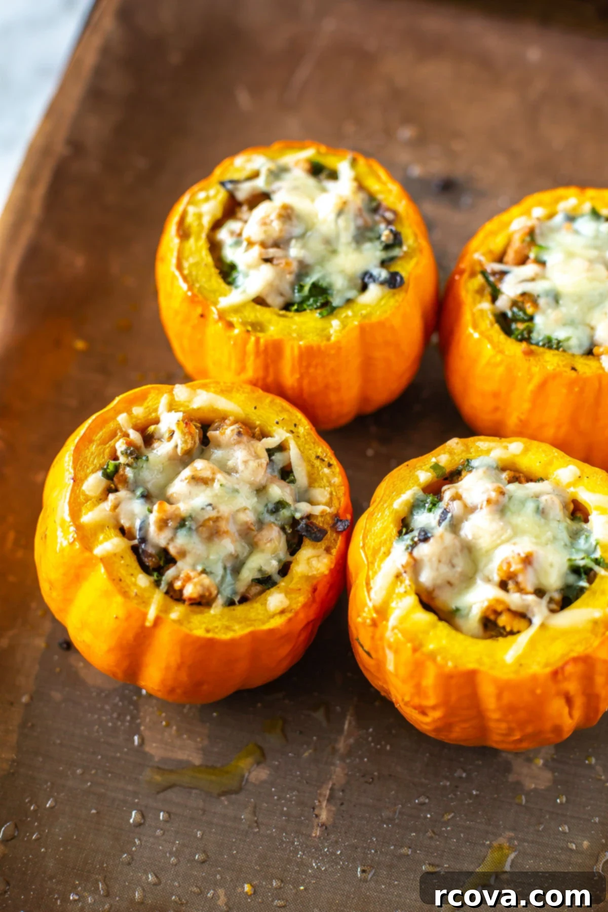 Unutulmaz Balkabağı Dolması Tarifi 8 Four golden-brown stuffed mini pumpkins, generously topped with melted Gruyere cheese, arranged on a baking sheet fresh out of the oven, ready to be served.