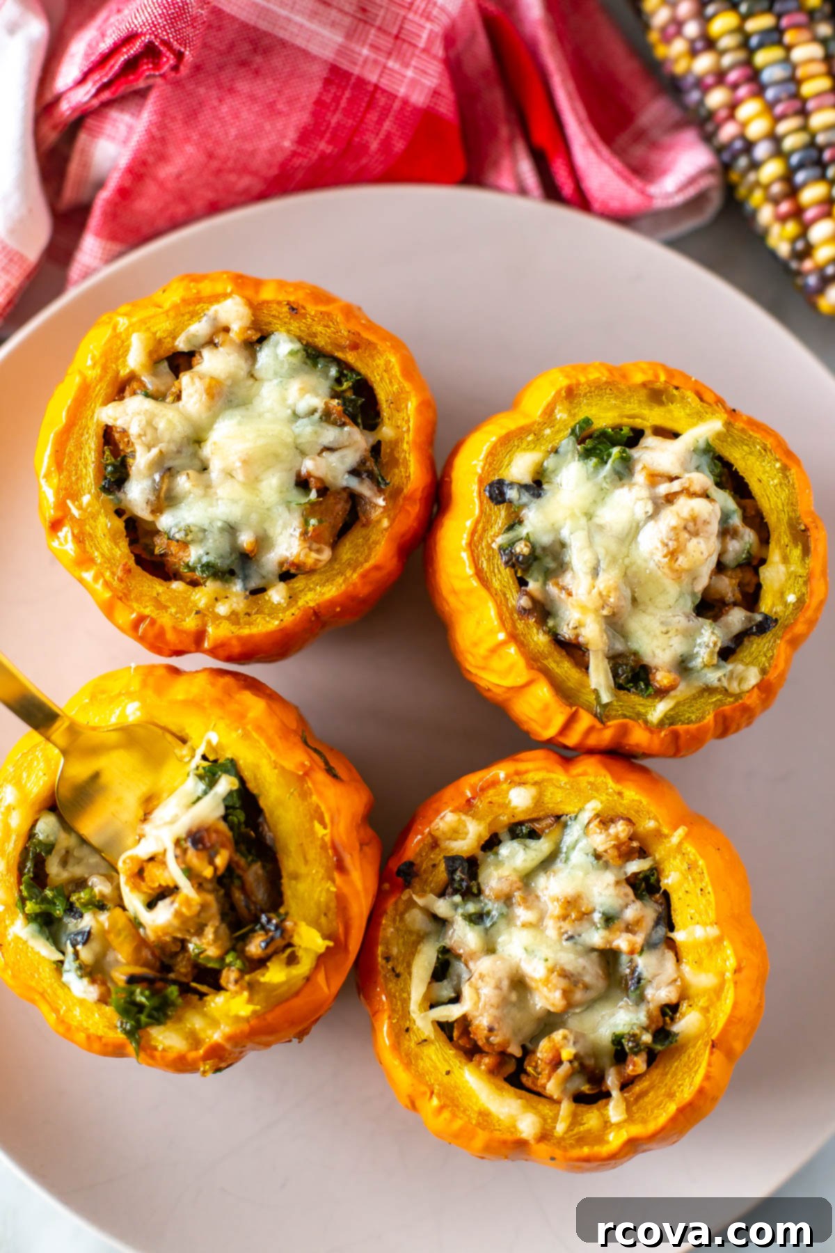 Unutulmaz Balkabağı Dolması Tarifi 9 A festive autumnal platter holds four perfectly baked stuffed mini pumpkins, each generously filled and topped with melted cheese, surrounded by decorative fall leaves and miniature gourds, setting a beautiful scene for a fall meal.