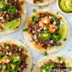 Crockpot Stovetop or Instant Pot Shredded Beef Tacos 11 Five shredded beef tacos, each with an assortment of toppings on top.
